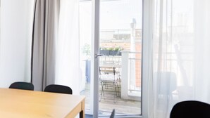 A room with a wooden table, a chair, a sliding glass door leading to an outdoor balcony with a table and chairs. - White and black by Prater #40 (Vienna)