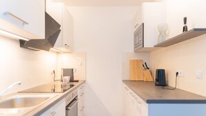 A narrow kitchen with a microwave, coffee machine, and a knife block on the countertop. - White and black by Prater #40 (Vienna)