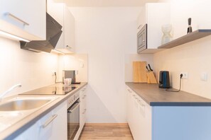 A narrow kitchen with a microwave, coffee machine, and a knife block on the countertop. - White and black by Prater #40 (Vienna)