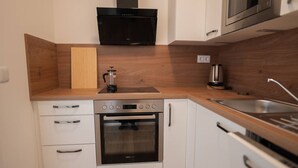 A compact kitchen with a built-in oven, a coffee maker, and a microwave. - Cozy Penthouse with a terrace by Schönbrunn Palace (Vienna)