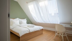A bedroom with a bed, a desk, and a chair. - Cozy Penthouse with a terrace by Schönbrunn Palace (Vienna)