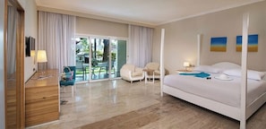 Ein Hotelzimmer mit Bett, Schreibtisch, Stuhl, kleinem Tisch und Blick ins Freie.
