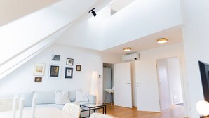 A modern living room with a sloped ceiling, a sofa, a coffee table, and framed pictures on the wall. - Two leveled Penthouse Schönbrunn (Vienna)