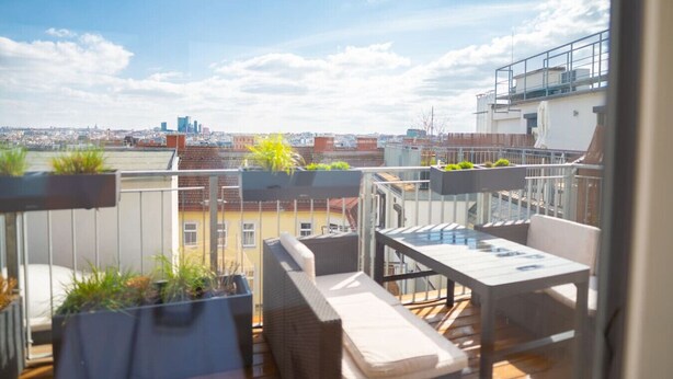 A rooftop terrace with outdoor furniture, potted plants, and a city view. - Two leveled Penthouse Schönbrunn (Vienna)