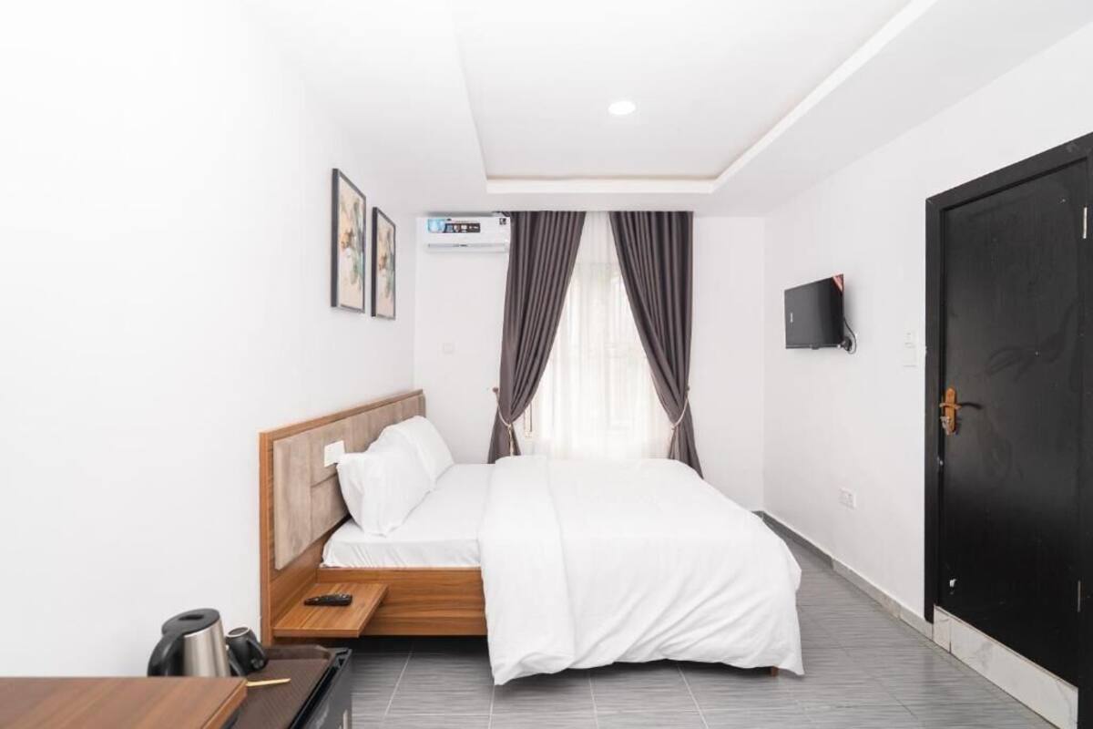 Une chambre d’hôtel équipée d’un lit, d’un bureau, d’une chaise, d’une machine à café, d’une télévision et d’une porte.