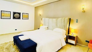 Een moderne slaapkamer met dakraam, een groot bed, nachtkastje en wandlampen.