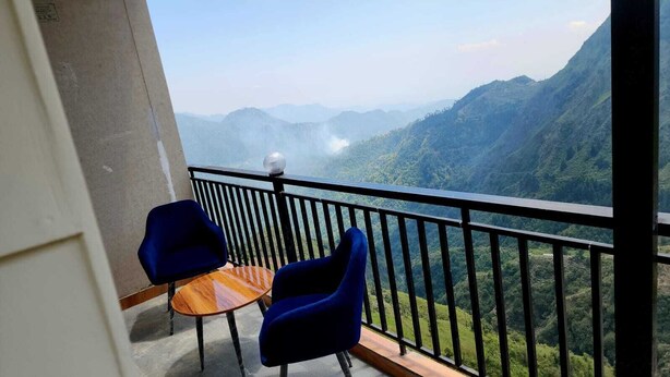 A balcony with a table and two chairs, overlooking a mountainous landscape. - Hazy hill  (Mussoorie)