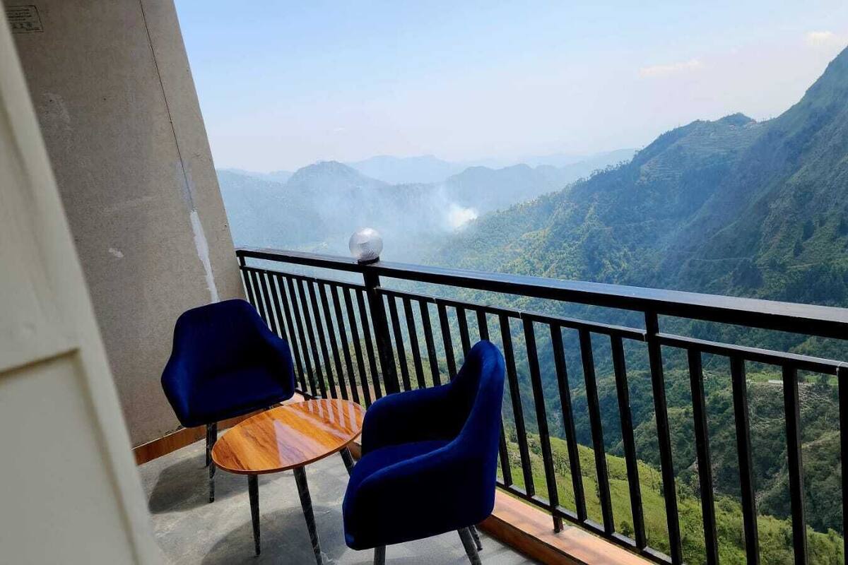 Un balcón con una mesa y dos sillas, con vistas a un paisaje montañoso.