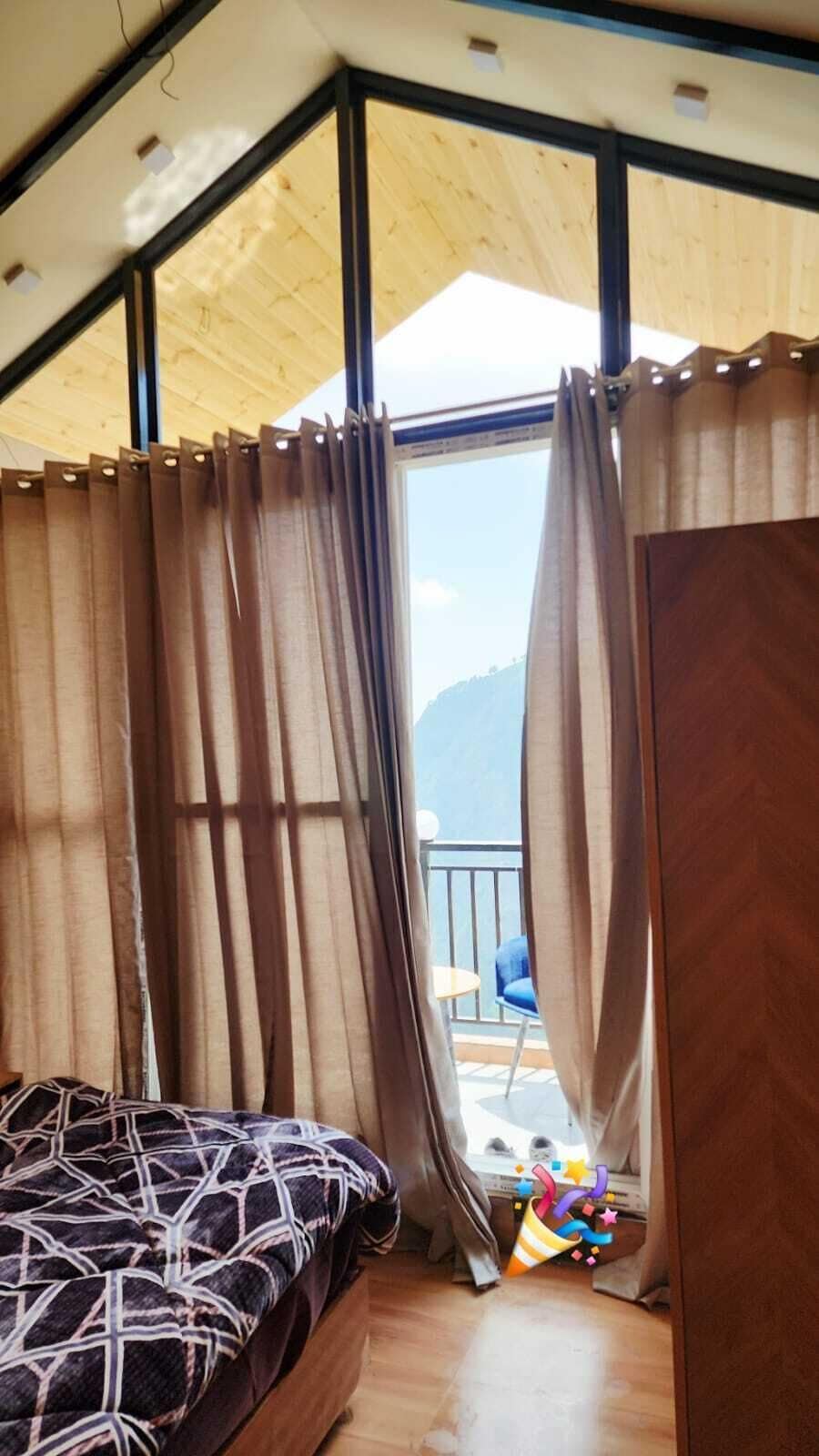 Huone, jossa on sänky, verhot, näkymä ulos ja parveke.