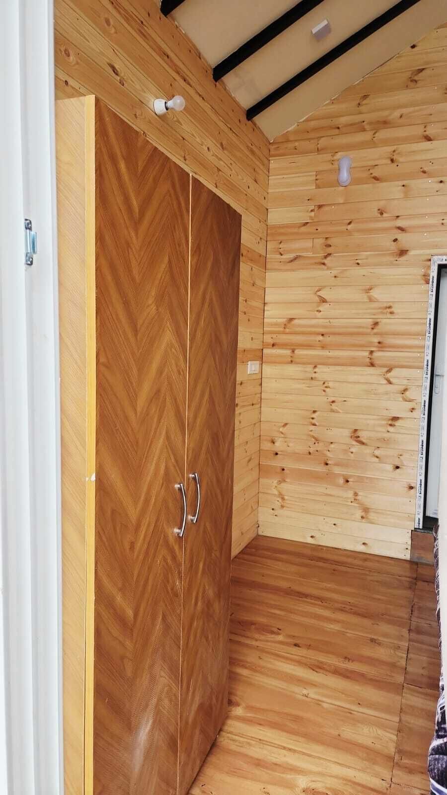 Ein Zimmer mit Holzwänden und Holzboden, einer Tür mit zwei Griffen und einer Decke mit freiliegenden Balken.