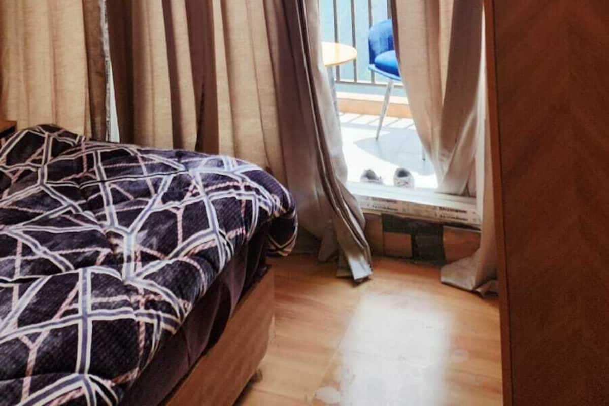 Una habitación con cama, un armario de madera y un balcón con una silla.