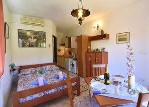 Un dormitorio con cama, una mesita con una botella y una silla.