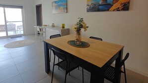 Ein Essbereich mit Holztisch, schwarzen Stühlen, einer Vase mit Blumen und zwei Bildern an der Wand.