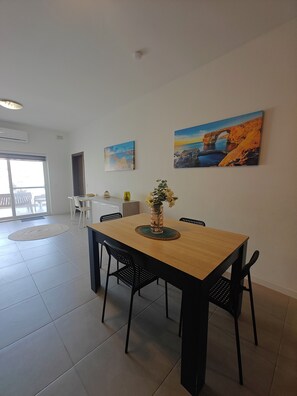 A dining area with a wooden table, black chairs, a vase with flowers, and two paintings on the wall.
