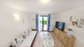 Een moderne woonkamer met een bank, televisie en een eethoek.