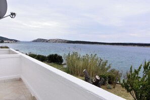 A balcony with a view of a calm sea, a white railing, and a satellite dish. - Seafront apartment on the Island of Rab (Rab)