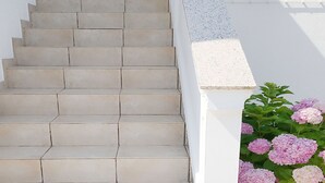 A staircase leading up to a white wall, with a planter of pink flowers on the right. - Cozy seafront flat on the Island of Rab (Rab)