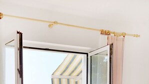 A hotel room with a bed, a bathroom with a mirror, and a view of the sea. - Cozy seafront flat on the Island of Rab (Rab)
