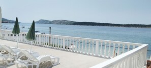 A balcony with white railings, a view of the sea, and white lounge chairs. - Cozy seafront flat on the Island of Rab (Rab)
