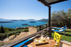 A terrace with a wooden table, a yellow chair, and a tray with drinks. - Villa Samsel - magnificent sea views, privacy, infinity pool, close to the beach (Perigiali)