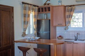 A kitchen with wooden cabinets, a stainless steel refrigerator, a sink, and two bar stools. - Villa Samsel - magnificent sea views, privacy, infinity pool, close to the beach (Perigiali)