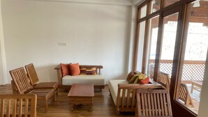 Une pièce meublée de meubles en bois, avec un canapé, une table et de grandes fenêtres.