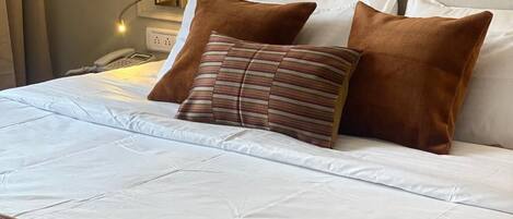 A neatly made bed with a patterned throw, a bedside lamp, and a phone on the nightstand.