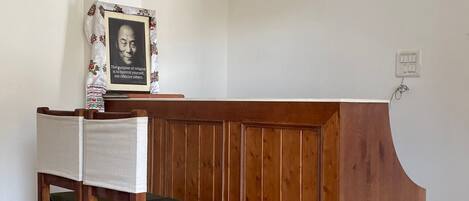 Un mostrador de recepción con detalles de madera, dos sillas con cojines verdes y una lámpara colgante.