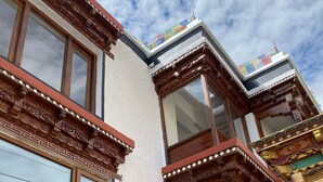 Un bâtiment doté d’éléments architecturaux traditionnels, notamment de balcons en bois richement décorés et surplombant un ciel dégagé.