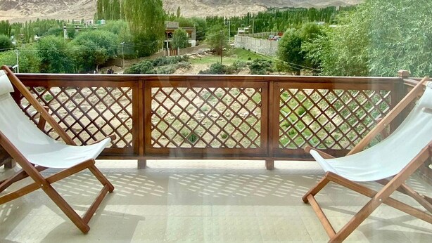 Un balcon avec vue sur les montagnes et un ciel dégagé.