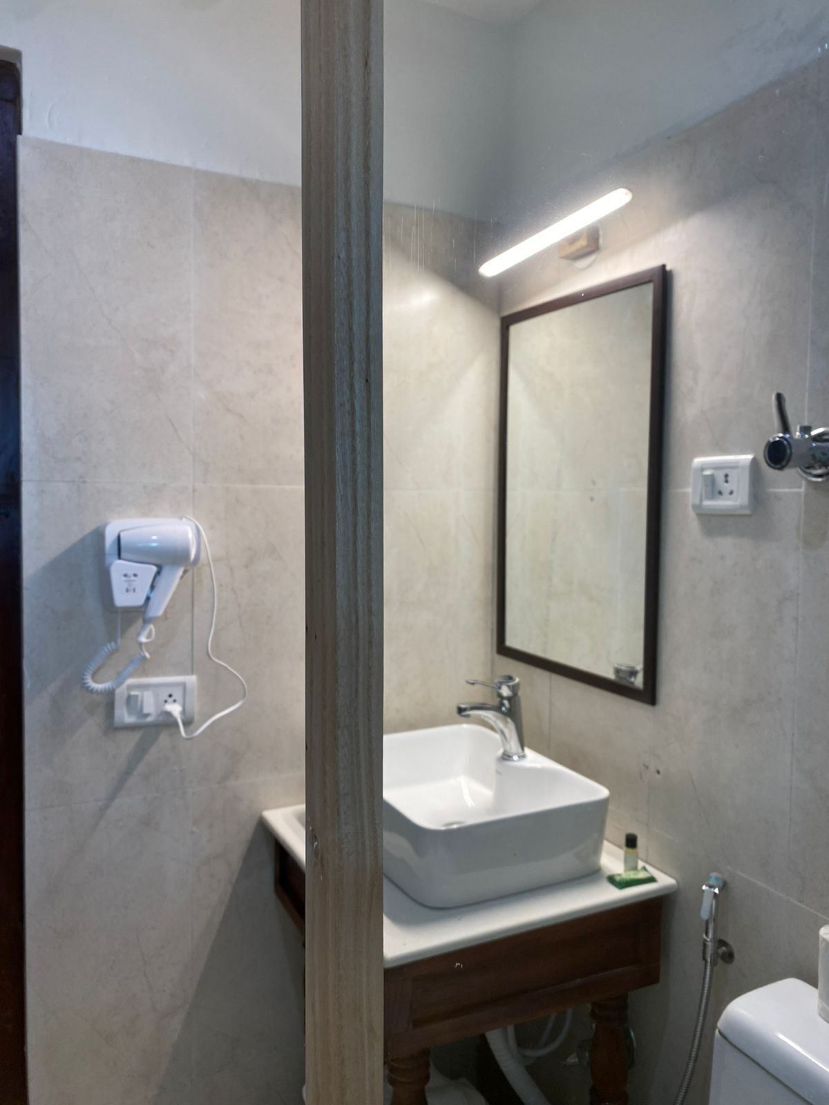 Baño con lavamanos, espejo, secador de pelo y ducha.