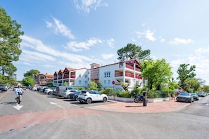 Straatbeeld met geparkeerde auto's, een fietser en een gebouw met balkons.