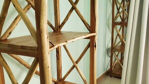 A wooden shelving unit with multiple shelves, a tiled floor, and a plain wall in the background.