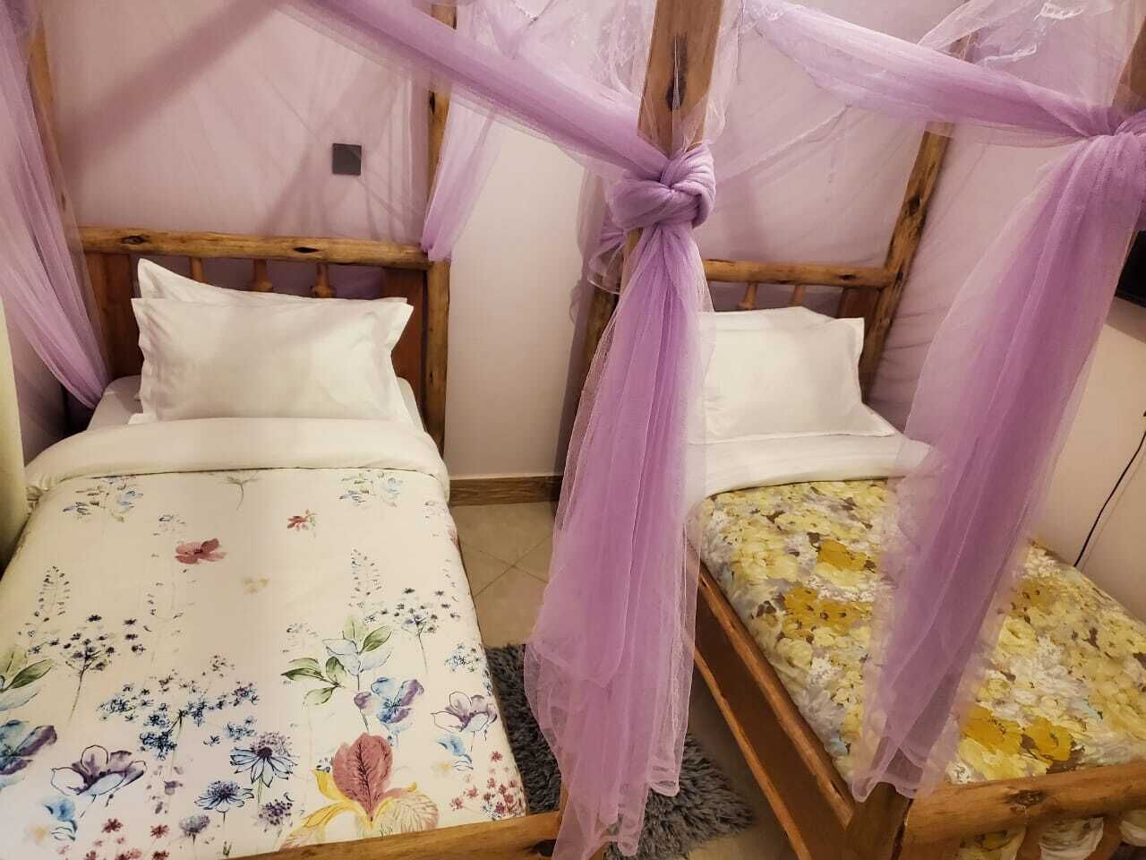 Een kamer met twee houten bedden, elk voorzien van een hemelbed.