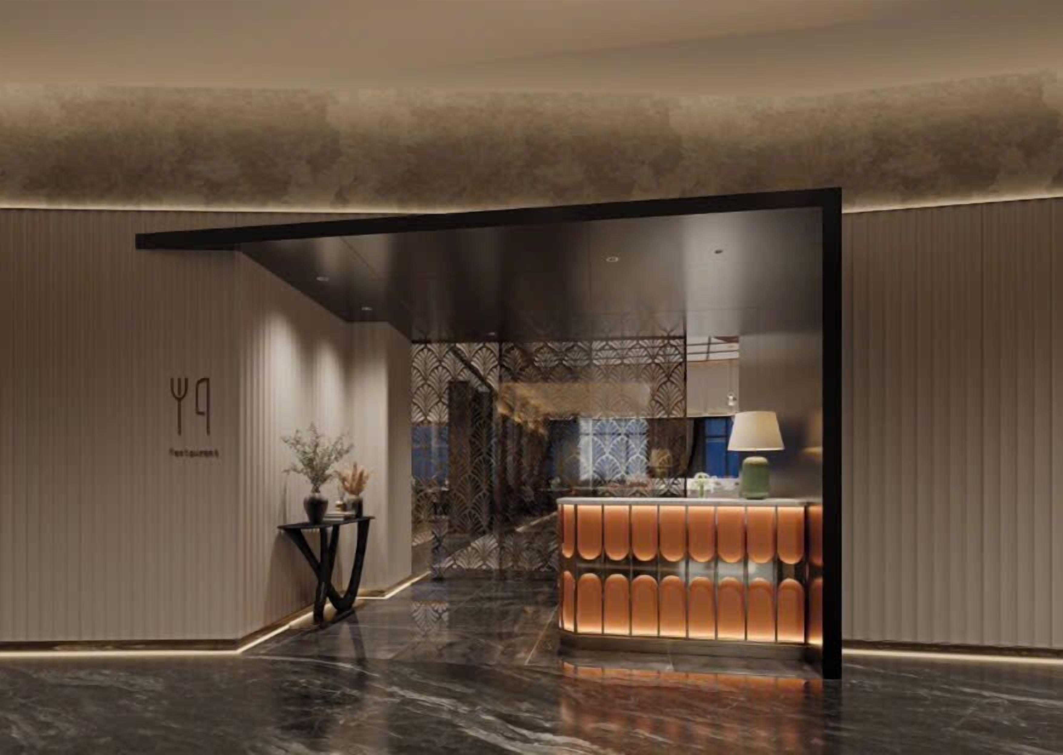 A modern hotel lobby with a reception desk, a seating area, and a decorative wall.