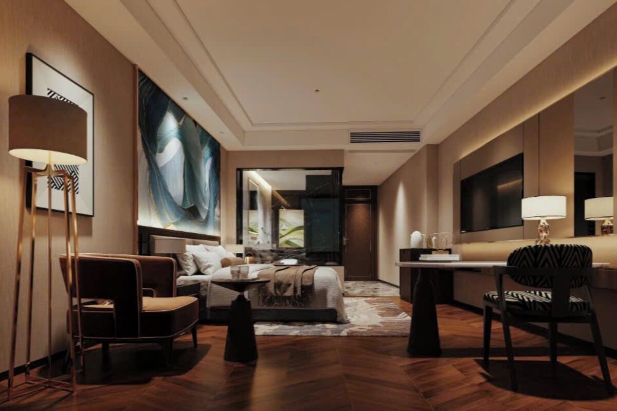 A modern hotel room with a large bed, a sitting area with a sofa and armchairs, a desk, and a large mirror.