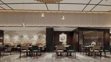 A hotel dining area with multiple tables and chairs, a large mural on the wall, and hanging pendant lights.