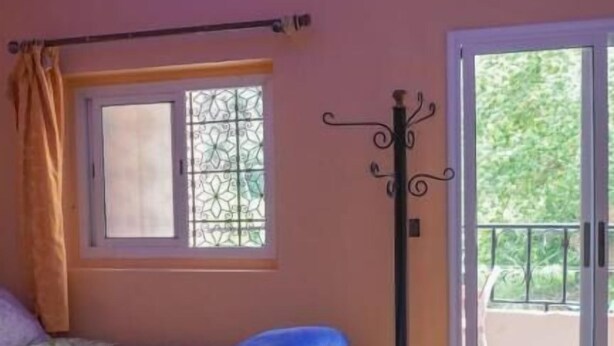 A bedroom with a bed, a window with a view, and a balcony door. - Hôtel Restaurant ASGAOUR (Asgaour)