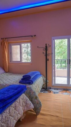 Un dormitorio con cama, ventana con vistas y puerta al balcón.
