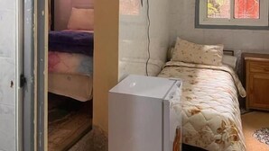 A bedroom with a bed, a small white refrigerator, a wall-mounted TV, and a window with a view of trees. - Hôtel Restaurant ASGAOUR (Asgaour)