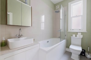 A bathroom with a sink, bathtub, toilet, and a shower. - Refined 2BD Home in Fulham (London)