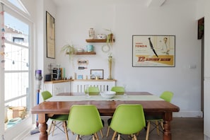 A dining area with a wooden table, green chairs, and a poster on the wall. - Refined 2BD Home in Fulham (London)