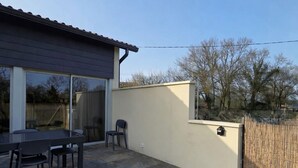 A patio with a table and chairs, a covered area, and a fenced yard. - Villa ma sueur - house with a story. (Coutras)