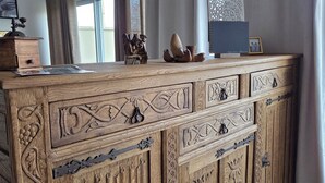 A wooden cabinet with intricate carvings, a small wooden chest, and a framed picture on top. - Villa ma sueur - house with a story. (Coutras)