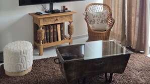 A living room with a flat-screen TV, a wicker chair, a glass coffee table, and a bookshelf. - Villa ma sueur - house with a story. (Coutras)