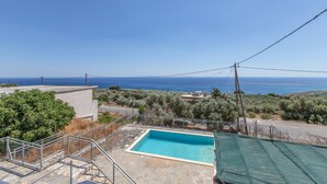 A swimming pool with a view of the sea, surrounded by stone steps and greenery.