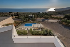Terraço com piscina, área de estar externa e vista para o mar.