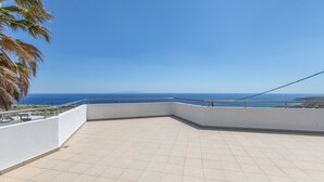 A rooftop terrace with a clear view of the sea and distant mountains.