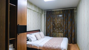 Una camera da letto con un letto, un armadio e una finestra con tende.