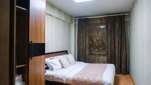 Ein Schlafzimmer mit Bett, Kleiderschrank und einem fensterbehangenen Fenster.
